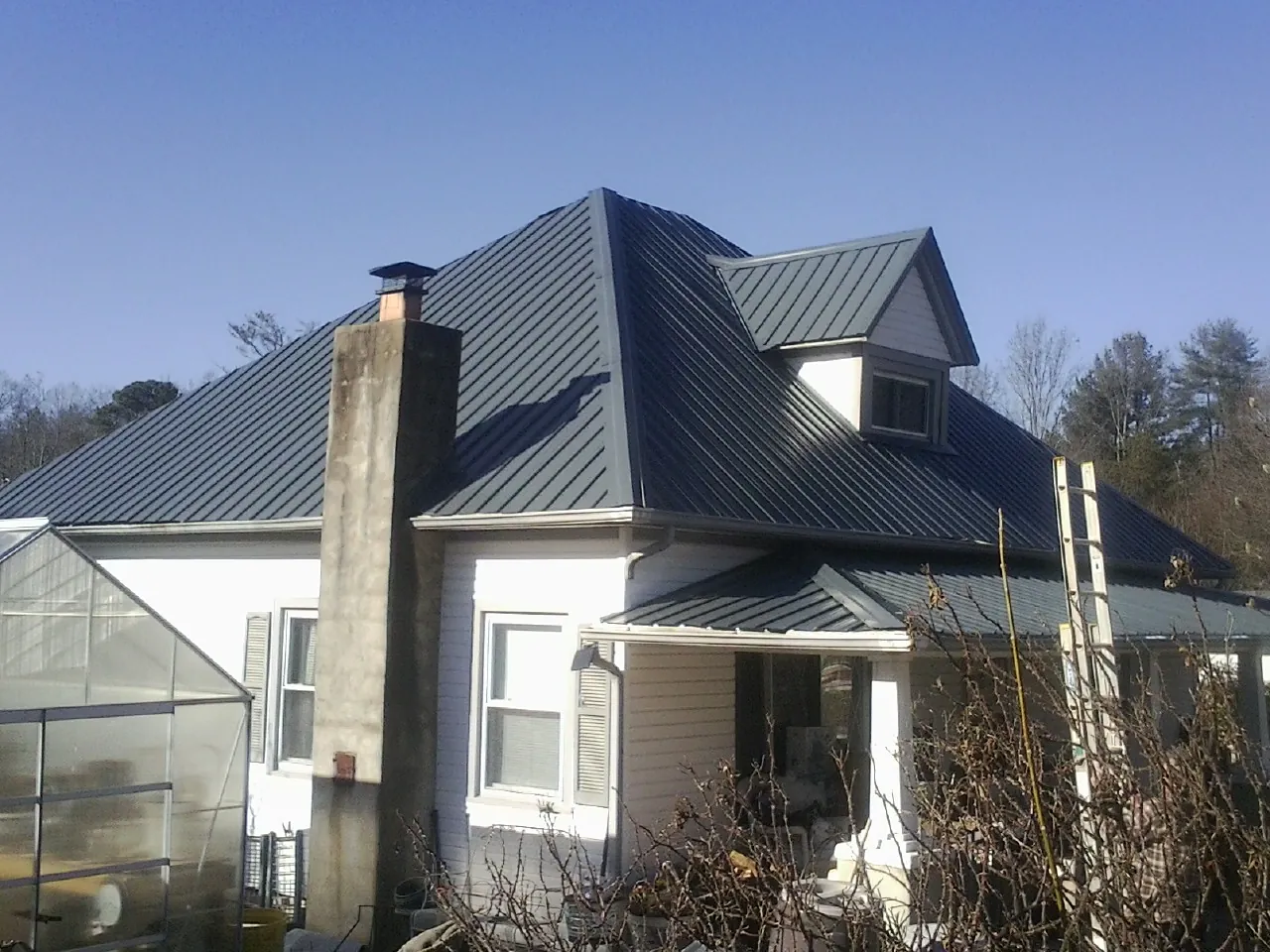 Dark blue standing seam metal roof on a white farmhouse with dormer — Slate & Tile Roof Repair by Roofing Brothers in Willow Hill
