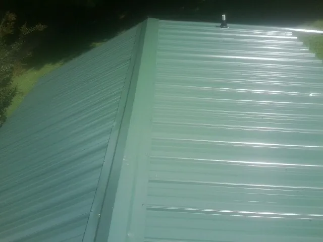 New green metal panels meeting at the ridge of a roof — Flat Roof Repair work by our crew in Willow Hill