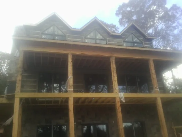 Dormers and porch framing on a large log home under construction — Roof Coating work by our crew in Willow Hill