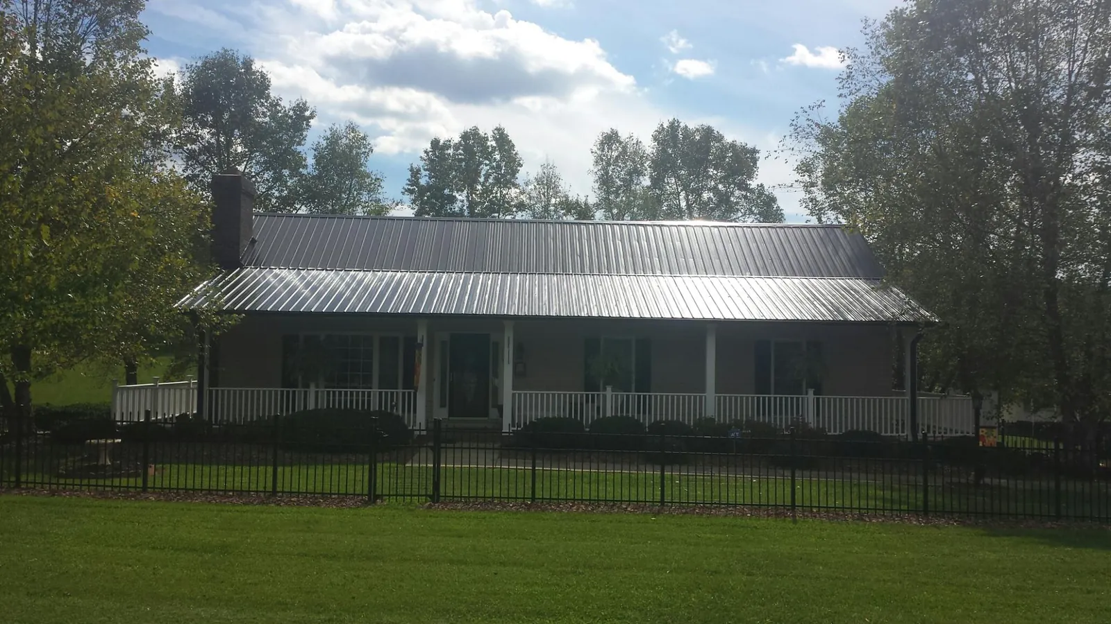 Gray metal roof on a brick ranch with a full width front porch — Gutter Guard Installation work by our crew in Willow Hill