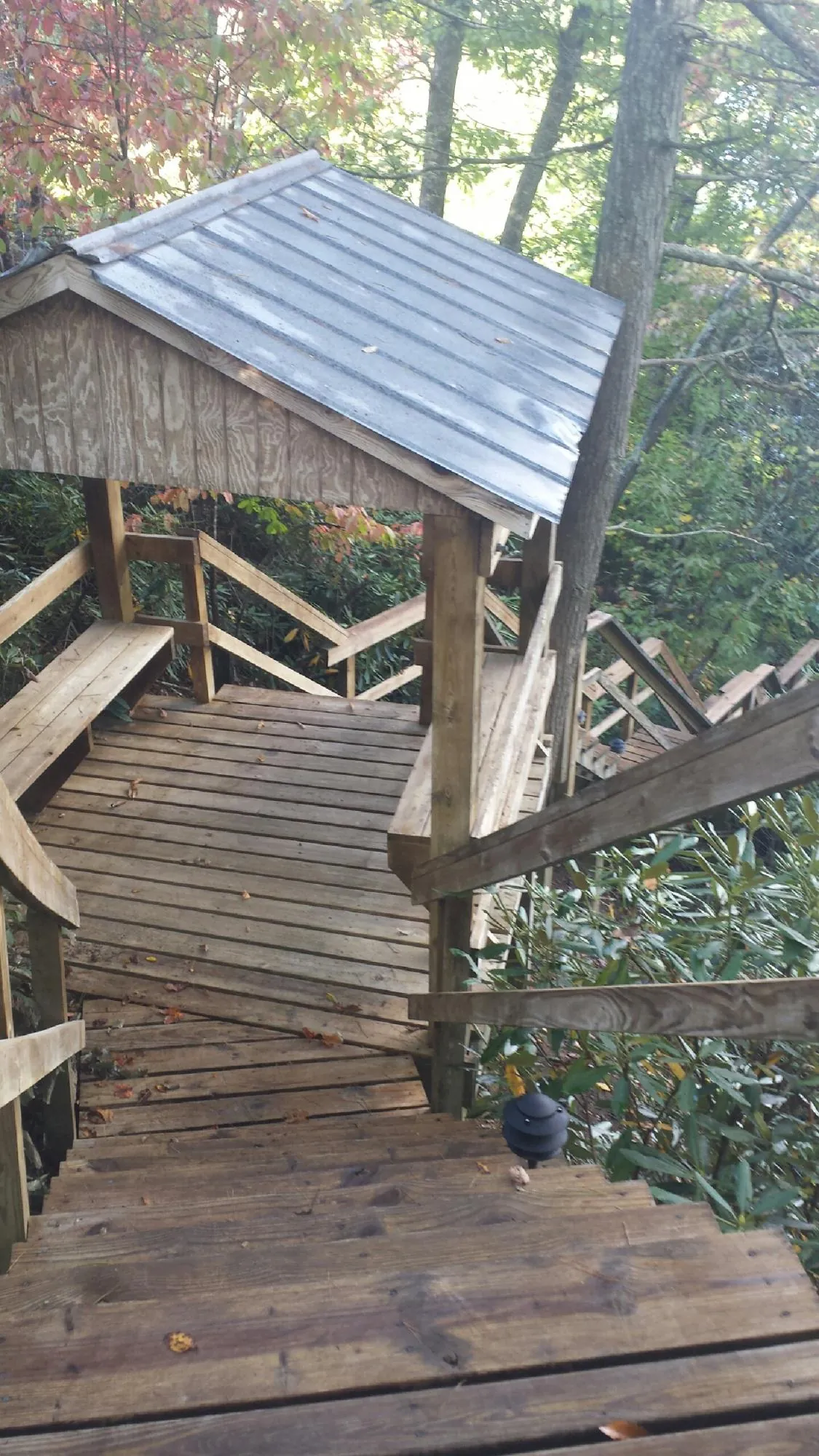 Metal roofed shelter over wooden steps on a wooded walkway — Skylight Repair & Installation work by our crew in Willow Hill