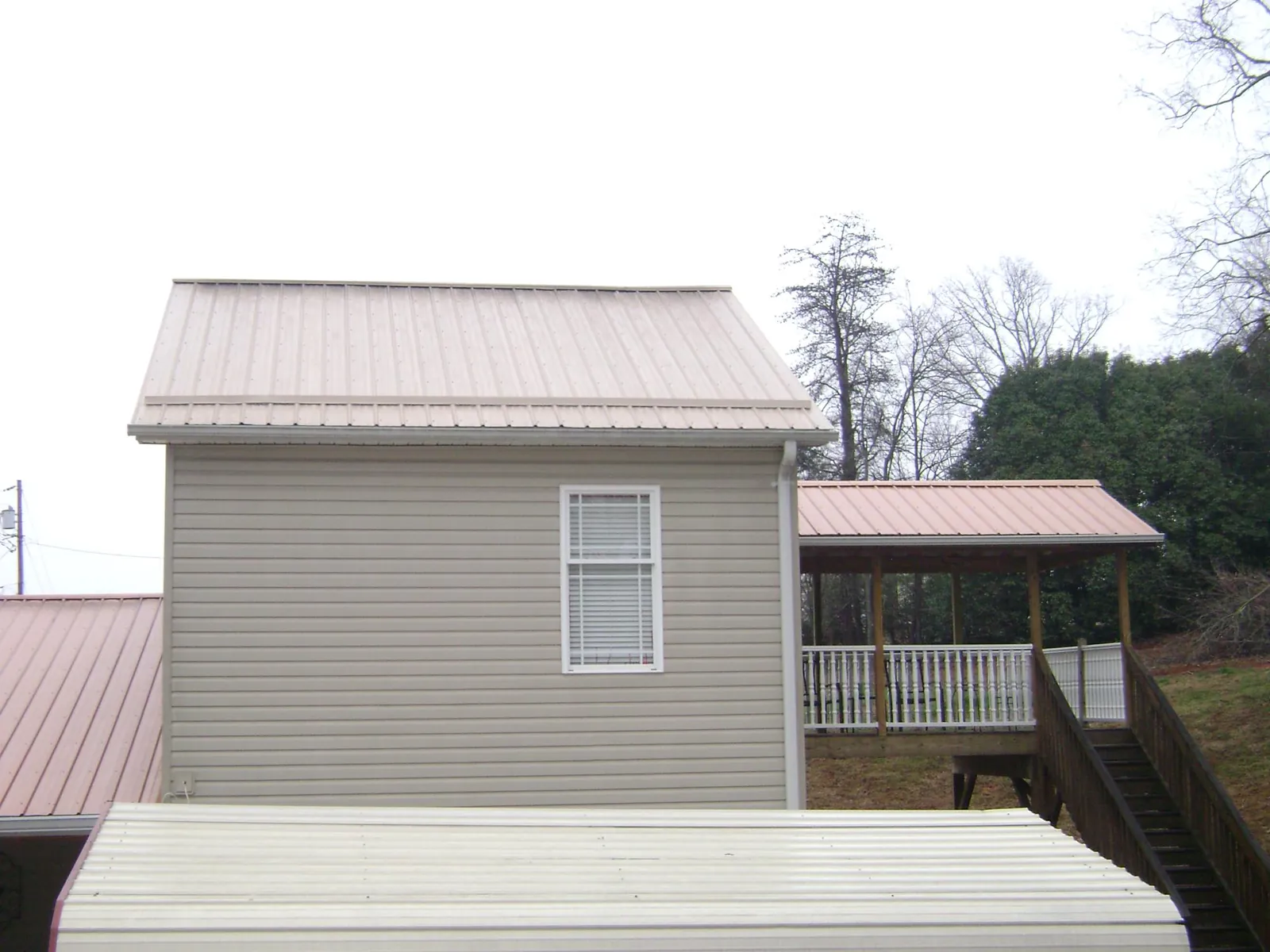 Tan metal roofs on a two story addition and attached porch, from a Roof Replacement job in Willow Hill
