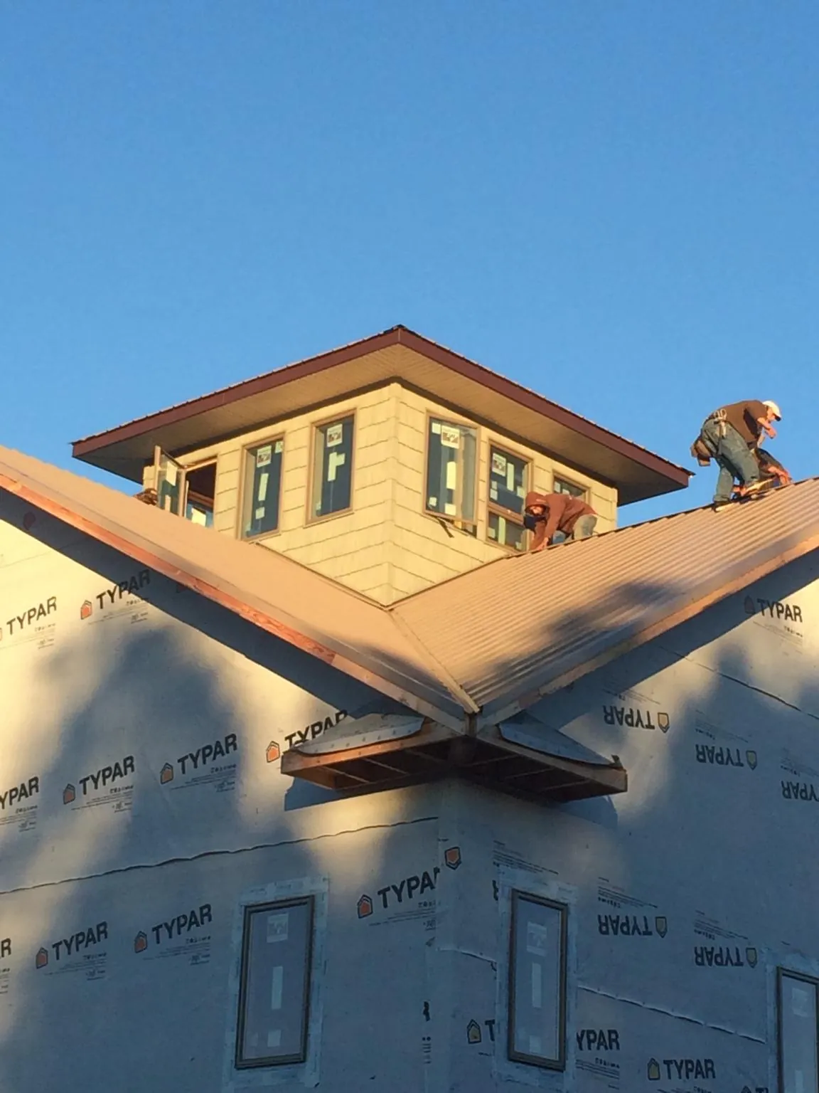 Roofers working around a rooftop cupola on a new metal roof at sunset — Roof Waterproofing in Willow Hill by Roofing Brothers